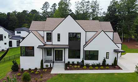 Exterior home remodel with bright white exterior walls, black accent trim, large windows, and a new roof built by Elik.